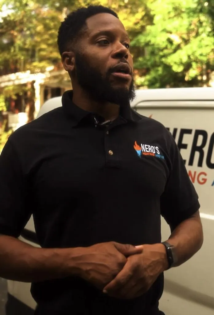Julian, founder of Nero's Heating & Air, wearing a branded polo shirt, speaking outdoors in front of a service van, emphasizing customer-focused HVAC service.