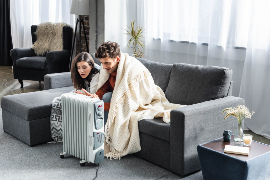 Couple huddling near a space heater. Heat pump maintenance can help avoid this situation in Cheverly, Maryland with regular checkups.