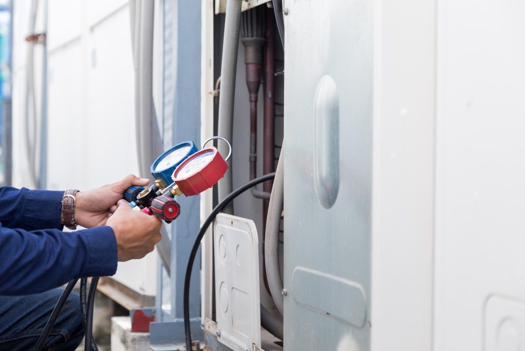 Washington DC: HVAC tech uses gauges to check freon levels on an air conditioning unit during maintenance. The person is in Cheverly, Maryland.