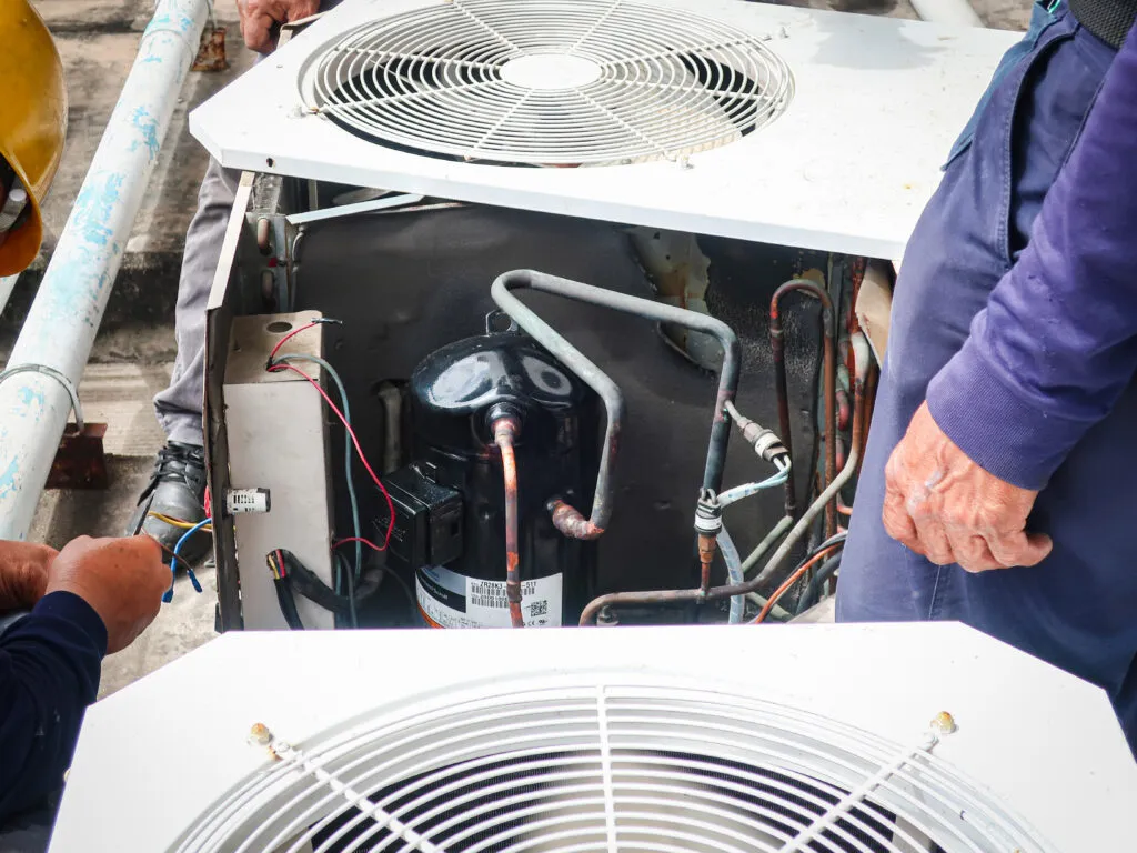 HVAC system maintenance in District Heights, Maryland: technicians repair the unit, showing components like the compressor and wiring inside.